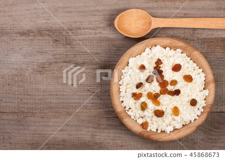 Cottage cheese with raisins in a wooden bowl on old wooden background with copy space for your text Cottage cheese with raisins in a wooden bowl on old wooden background with copy space for your text 45868673