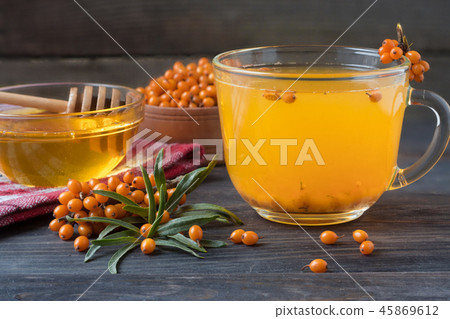 Tea of sea-buckthorn berries with honey and a branch on wooden background 45869612