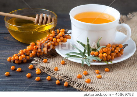 Tea of sea-buckthorn berries with a sprig on sackcloth and wooden background Tea of sea-buckthorn berries with a sprig on sackcloth and wooden background 45869798