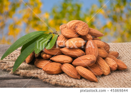 heap of peeled almonds with leaf on a wooden table blurred garden background heap of peeled almonds with leaf on a wooden table blurred garden background 45869844
