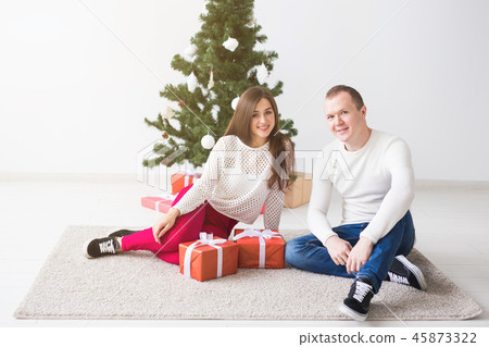 Sweet couple opening Christmas gifts, sitting in the living room. 45873322