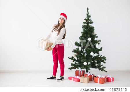 Christmas, holidays and presents concept - young woman in santa hat holding a lot of gifts on white Christmas, holidays and presents concept - young woman in santa hat holding a lot of gifts on white 45873345