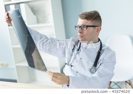 Medicine, healthcare and people concept - Handsome smiling doctor checking x-ray results Medicine, healthcare and people concept - Handsome smiling doctor checking x-ray results 45874020