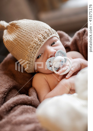 a small child in basket sucks pacifier in warm hat 45875176