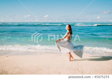 Pretty woman posing in blue dress at ocean beach. Pretty woman posing in blue dress at ocean beach. 45875255