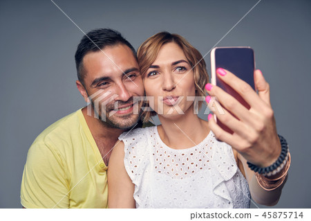 Happy couple in studio laughing over grey Happy couple in studio laughing over grey 45875714