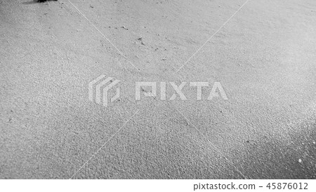 Black and white closeup image of wet sand on ocean beach 45876012