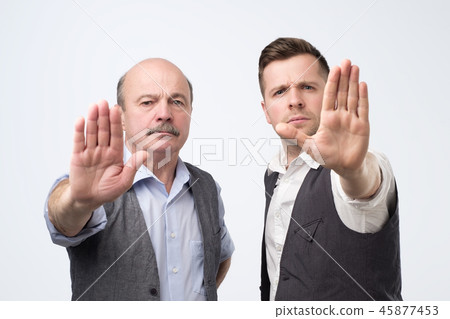 Two mature men giving showing stopt hands gesture Two mature men giving showing stopt hands gesture 45877453