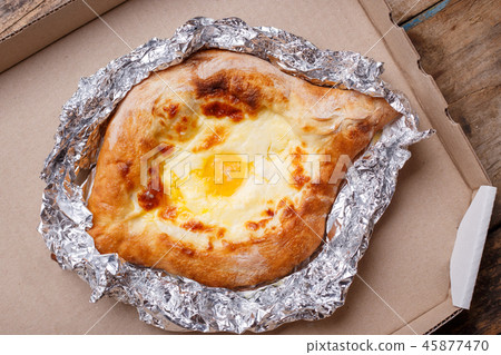 Adjarian open khachapuri with egg on wooden board 45877470