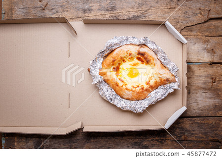 Adjarian open khachapuri with egg on wooden board 45877472
