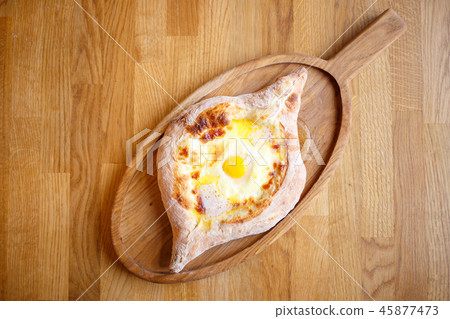 Adjarian open khachapuri with egg on wooden board 45877473