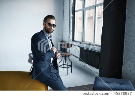 Young stylish businessman leader indoors at office wearing sunglasses looking aside thoughtful 45878987