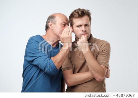 Senior man sharing secret or whispering gossips into his son ear. Telling family secret concept Senior man sharing secret or whispering gossips into his son ear. Telling family secret concept 45879367