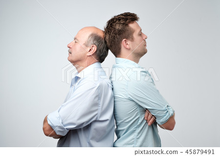 Side view of two serious men father and son standing back to back against a white background 45879491