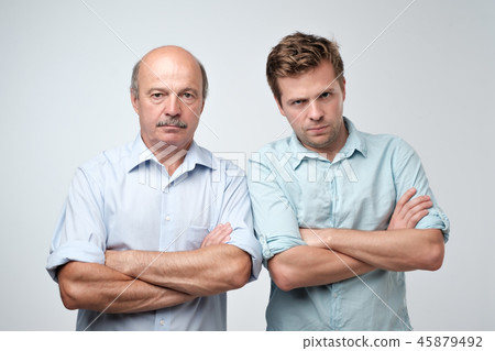 Portrait of mature father and son standing with serious expression on face. Good relatios in family. Portrait of mature father and son standing with serious expression on face. Good relatios in family. 45879492