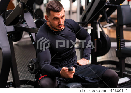Young handsome fitness trainer with stopwatch in modern gym Young handsome fitness trainer with stopwatch in modern gym 45880141