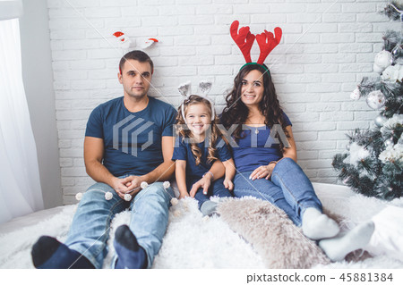 Christmas family photo. Father, mother and daughter are wearing christmas funny horns. 45881384