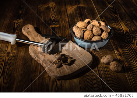 Walnuts in an old bowl with a kitchen ax 45881705