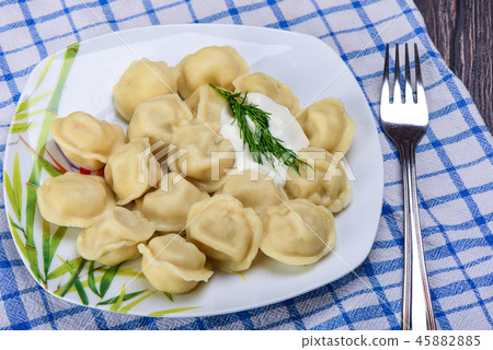 Portion of ravioli with sour cream and dill in a plate 45882885