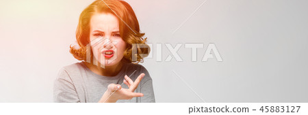 Charming young girl in a gray T-shirt on a gray background. The girl leads a dialogue 45883127
