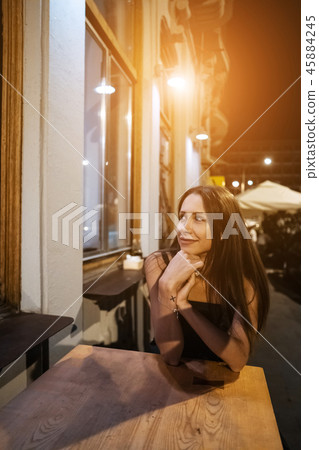 Gorgeous girl sitting alone in cafe at night . Gorgeous girl sitting alone in cafe at night . 45884245
