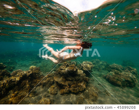 Split underwater photo of a girl snorkeling with mask in tropical ocean enjoying summer vacation on 45899208