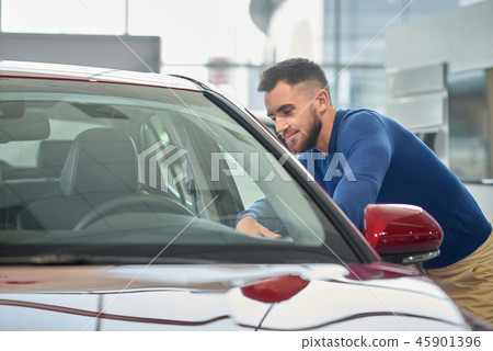 Handsome young man leaning on beautiful red car.  45901396