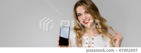 Attractive young blonde business woman in black and white clothes smiling holding mobile phone in 45902697