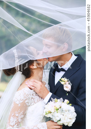 Bride and groom in a park kissing. Wedding couple in love Bride and groom in a park kissing. Wedding couple in love 45904682