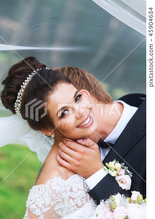 Bride and groom in a park kissing. Wedding couple in love Bride and groom in a park kissing. Wedding couple in love 45904684