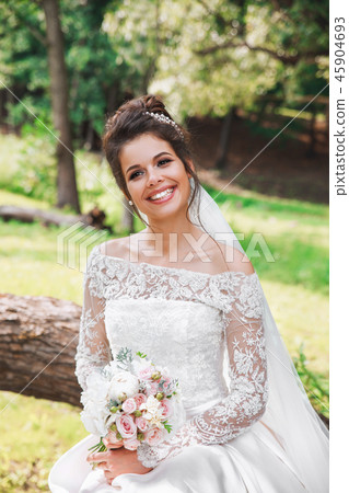 Beautiful happy bride with bouquet of flowers in park 45904693