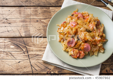 Stewed cabbage with sausages in a plate  45907802