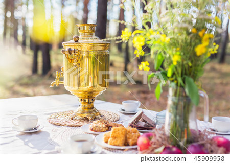 Russian samovar on the table with some snacks outdoors Russian samovar on the table with some snacks outdoors 45909958