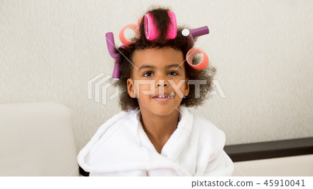 Black girl with curlers with hairpins in her hair. 45910041