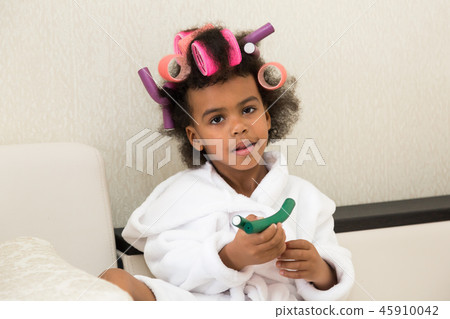 Black girl with curlers with hairpins in her hair. Black girl with curlers with hairpins in her hair. 45910042