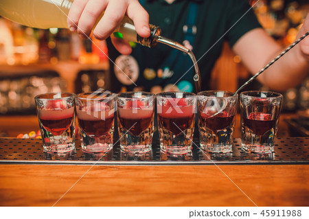 Bartender is pouring tequila into glass against the background of the bar. Bartender is pouring tequila into glass against the background of the bar. 45911988