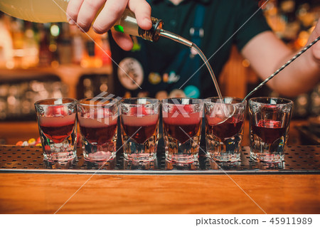 Bartender is pouring tequila into glass against the background of the bar. 45911989