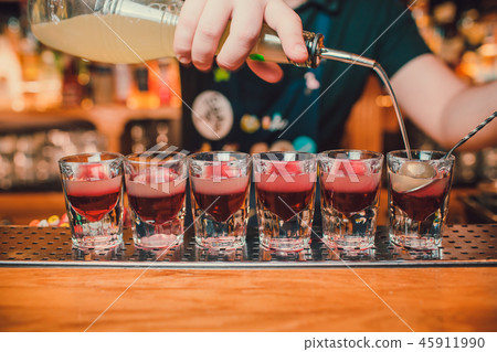 Bartender is pouring tequila into glass against the background of the bar. 45911990
