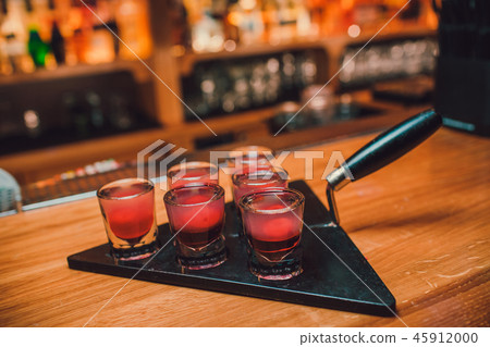 Bartender is pouring tequila into glass against the background of the bar. Bartender is pouring tequila into glass against the background of the bar. 45912000