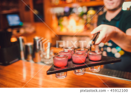 Bartender is pouring tequila into glass against the background of the bar. Bartender is pouring tequila into glass against the background of the bar. 45912100