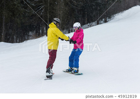 Young couple snowboarders slide down Young couple snowboarders slide down 45912819