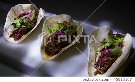 Three pork carnitas street tacos in yellow corn tortilla. 45913167