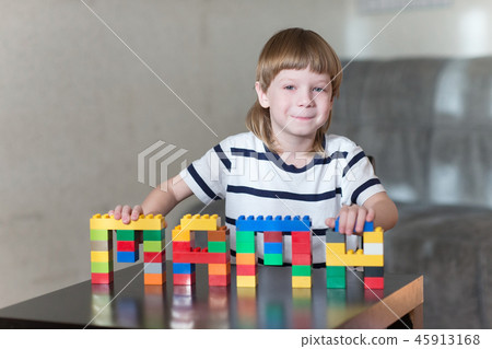 boy playing with lots of colorful plastic blocks indoor 45913168