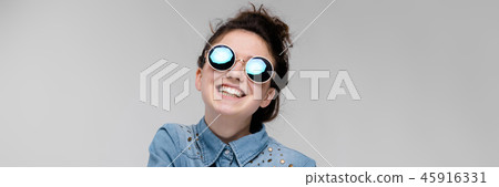 Young brunette girl in round glasses. Hairs are gathered in a bun. The girl folded her arms. 45916331