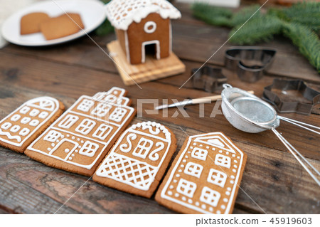 A lot of ginger biscuits in the form of European houses on brown wooden table. Decorated with white A lot of ginger biscuits in the form of European houses on brown wooden table. Decorated with white 45919603