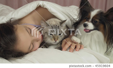 Beautiful teen girl sleeping sweetly in bed with dog and cat Beautiful teen girl sleeping sweetly in bed with dog and cat 45919604
