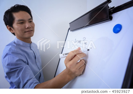 Young businessman writing on white board Young businessman writing on white board 45923927