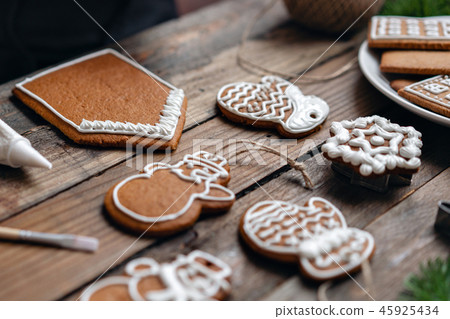 A lot of ginger biscuits in different form on brown wooden table. Decorated with white sweet glaze A lot of ginger biscuits in different form on brown wooden table. Decorated with white sweet glaze 45925434