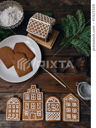 A lot of ginger biscuits in the form of European houses on brown wooden table. Decorated with white A lot of ginger biscuits in the form of European houses on brown wooden table. Decorated with white 45925509