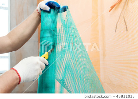 A worker is cutting  a fiberglass mesh. 45931033